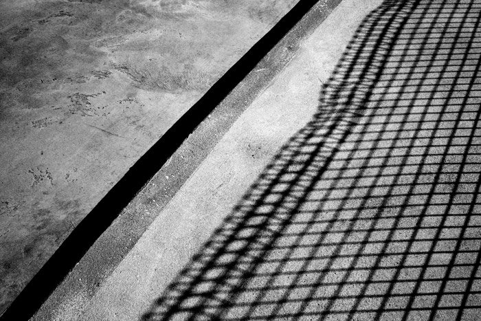 Теневая черно-белая фотография бетона с тенью от забора. 