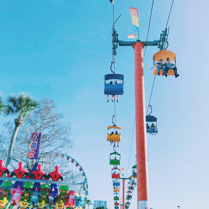 Фотография аттракционов на ярмарке в ясный день с голубым небом. 