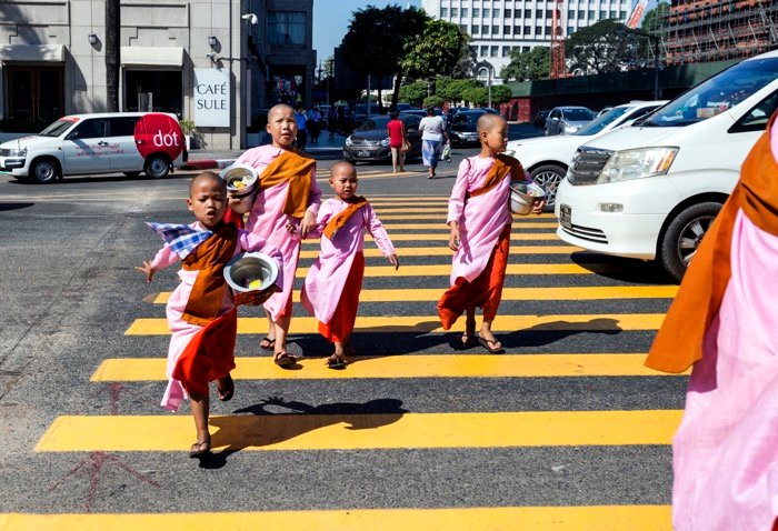 Группа детей в традиционной одежде переходит оживленную улицу - уличная фотография
