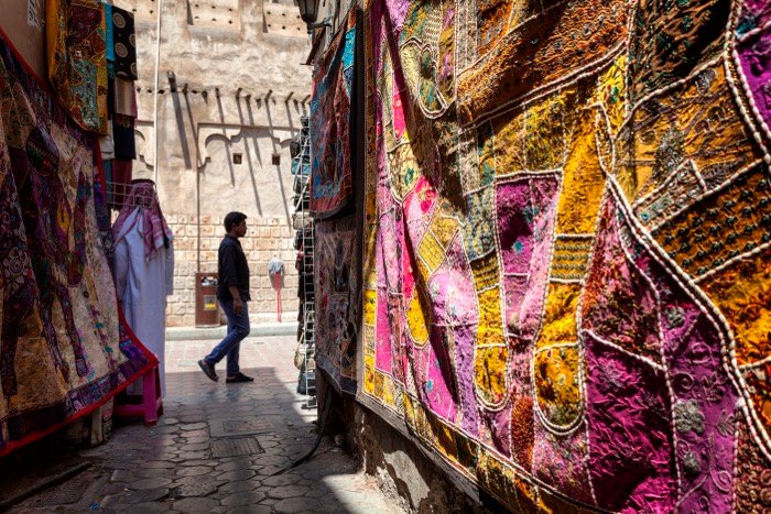 Рыночная сцена прохожего в обрамлении красочного материала на переднем плане - уличная фотография