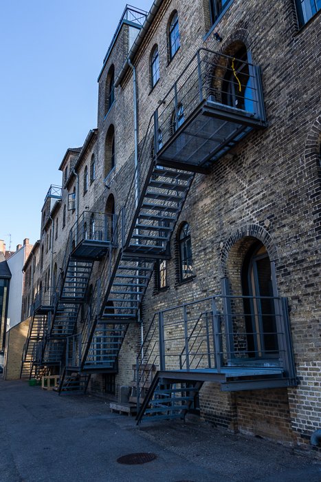 Сфотографированный город: Небольшой переулок с боковым видом на кирпичное здание в Копенгагене. 