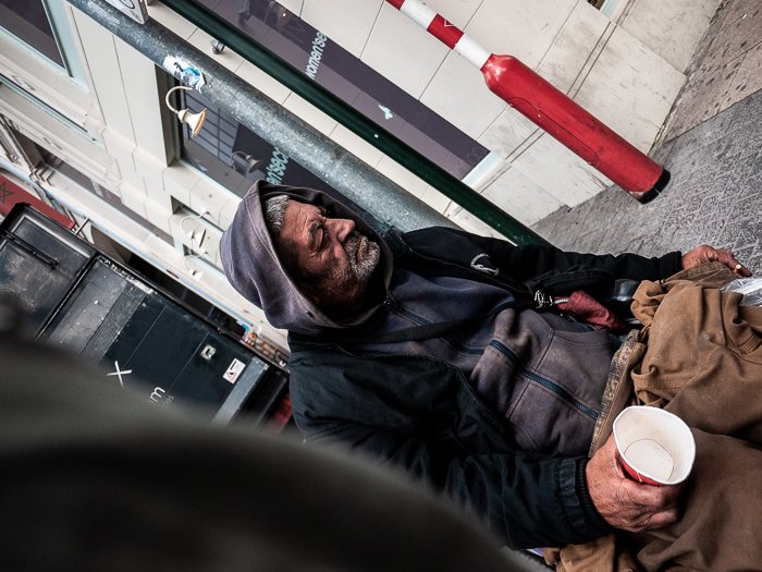 Снимок от бедра, наклоненная фотография бездомного в инвалидном кресле, держащего пустую чашку на городской улице