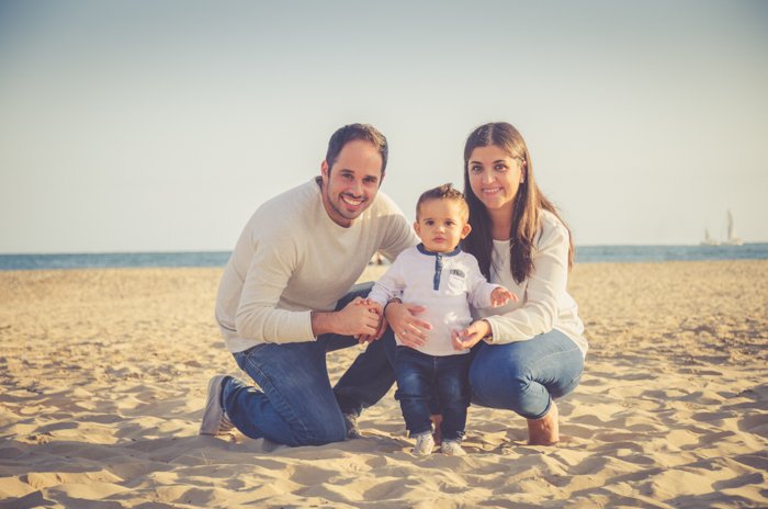 Семейная фотосессия пары и маленького ребенка, позирующих на пляже
