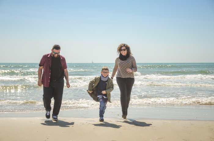 Семейное портретное фото пары и сына, идущих по пляжу