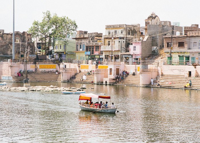 Лодка на реке мимо красочных зданий в Индии