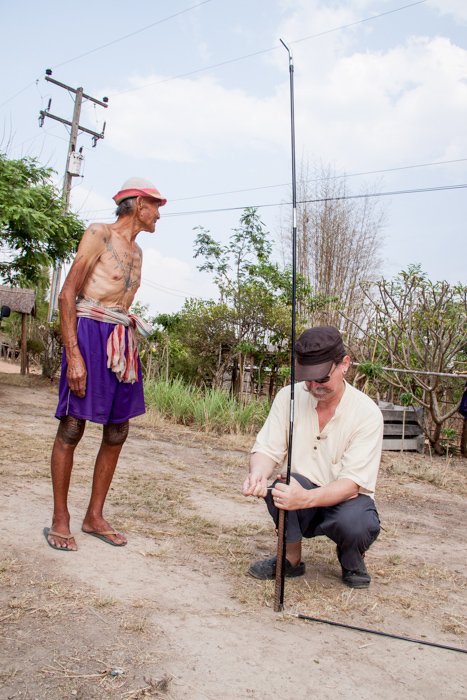 Каренский мужчина наблюдает за фотографом, устанавливающим студию портретной фотографии на открытом воздухе в районе Ом Кой, северный Таиланд.
