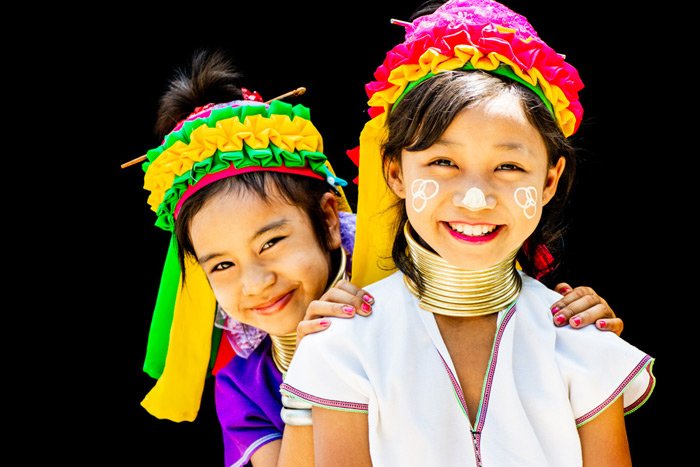 Фотография двух кайянских девочек, наслаждающихся тем, что их портрет сделан в студии портретной фотографии на открытом воздухе в их деревне на севере Таиланда.