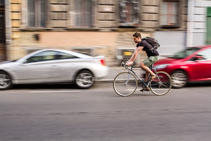 Велосипедист на улице с размытием движения на заднем плане