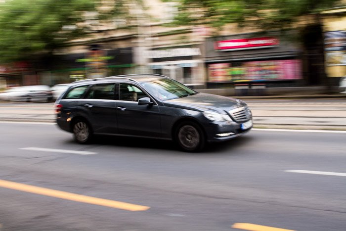 Размытый снимок серого автомобиля, едущего по улице