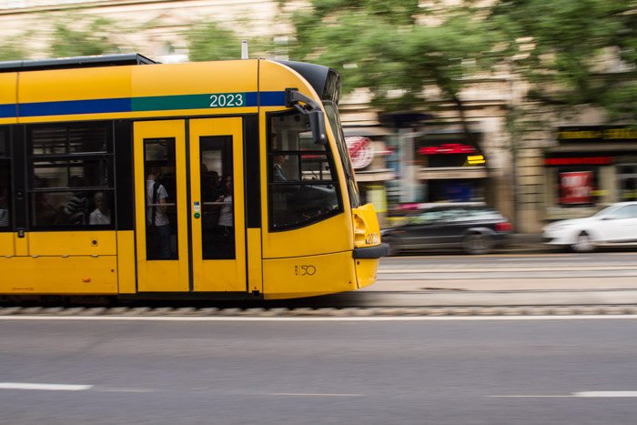 Снимок желтого трамвая, движущегося по улице