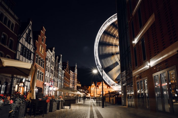 Уличная сцена ночью с движущимся колесом обозрения, снятая камерой с таймлапсом