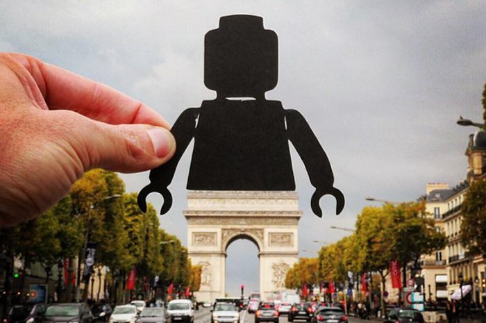 классная фотография с вынужденной перспективой человека, держащего силуэт фигурки Lego над Триумфальной аркой в Париже