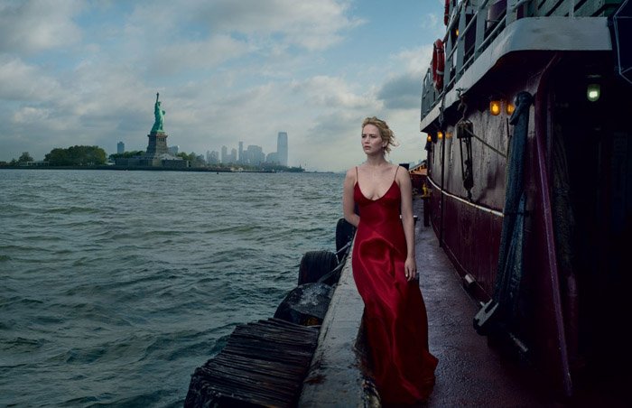 Annie Leibovitz портрет девушки в красном вечернем платье, стоящей на причале с морем и Эмпайр-стейт-билдинг позади нее