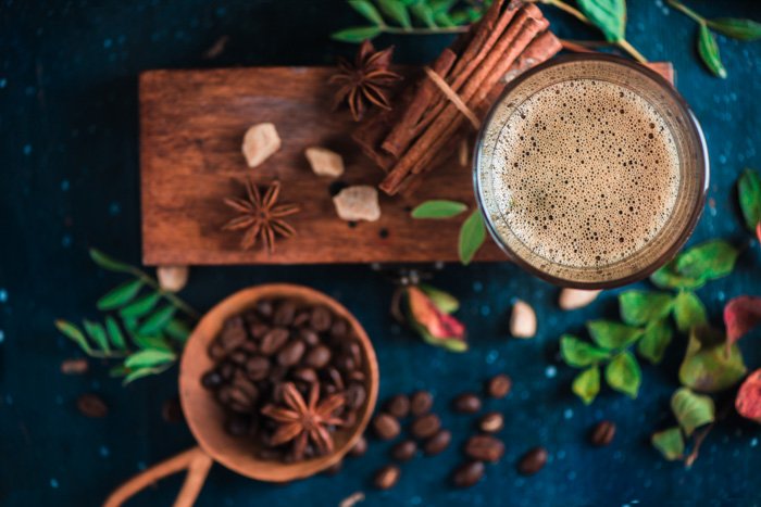 Изображение кофейных чашек, кофейных зерен, палочек корицы и листвы на деревянной доске
