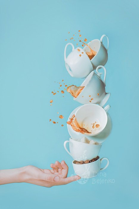 Забавная кофейная фотография шести падающих чашек, балансирующих на кончике пальца