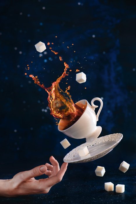 Забавная кофейная фотография падающей чашки, блюдца и сахарницы, балансирующей на кончике пальца