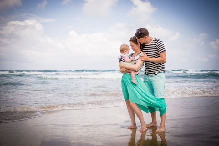 Lifestyle снимок пары с маленьким ребенком, стоящей на пляже - композиция для семейных портретов