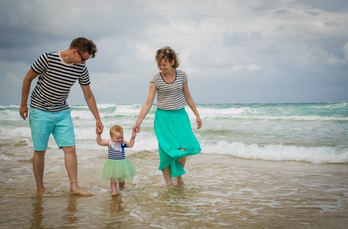 Casual shot of the couple holding a little baby on the beach - family portraits composition