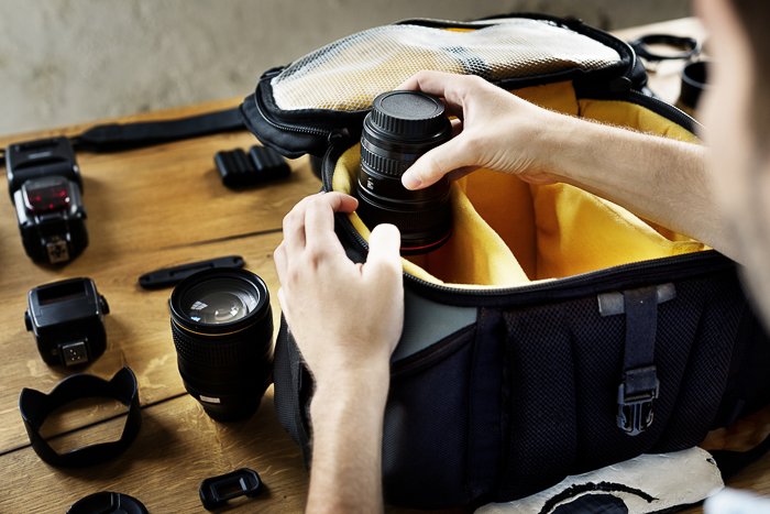 Человек, организующий свою сумку для фотокамеры в путешествии