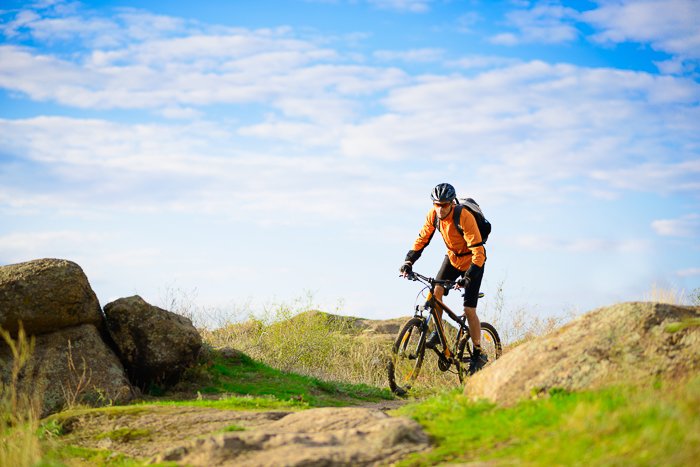 Горный велосипедист едет по травянистой сельской местности в яркий день