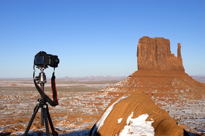 DSLR камера на штативе направлена на скалистый бесплодный пейзаж