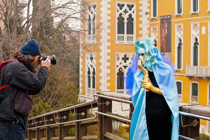 Мужчина фотографирует человека в экстравагантном карнавальном костюме во время туристической фотосессии