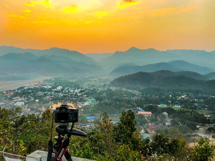 DSLR-камера Canon на штативе, направленная на красивый пейзаж на закате