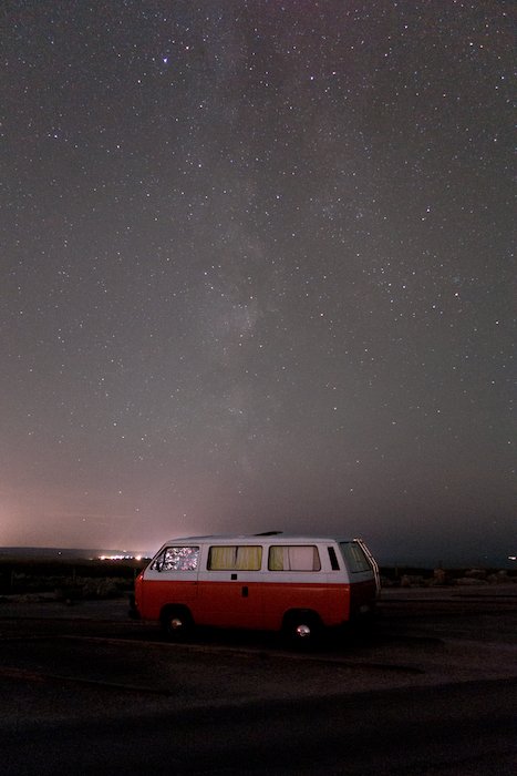 Изображение красного фургона, припаркованного под впечатляющим звездным небом