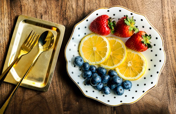 Снимок сверху роскошной тарелки с фруктами и золотыми столовыми приборами для будуарной съемки
