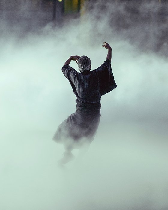 Атмосферный портрет человека, танцующего среди дыма или тумана