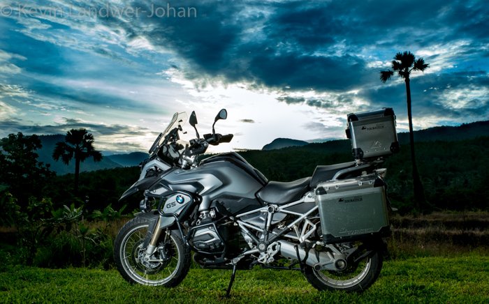 Серебристый мотоцикл с потрясающим пейзажем позади и водяным знаком сверху, созданный в lightroom.