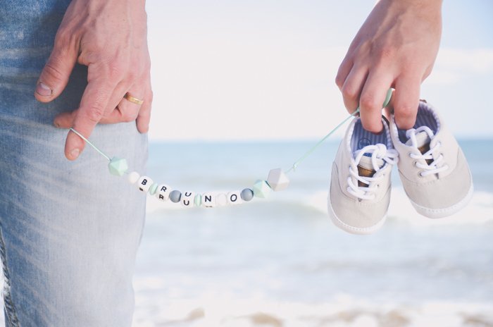 крупный план человека, держащего детские мотыжки и ожерелье на пляжной фотосессии