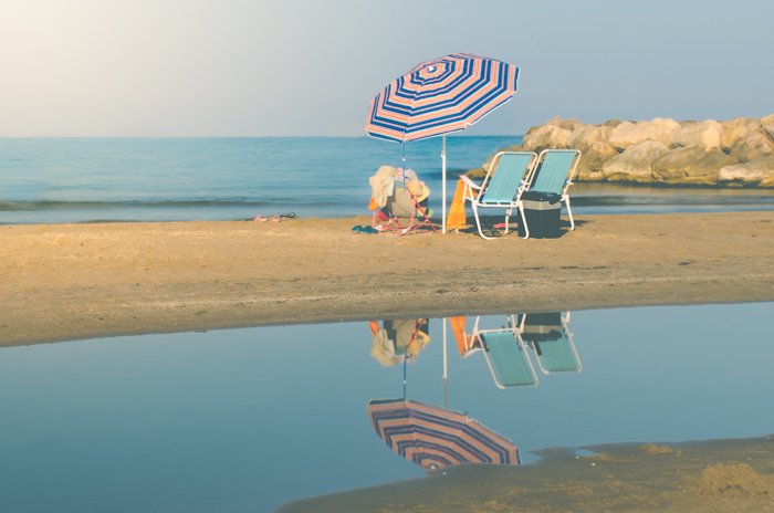 Безмятежное пляжное фото шезлонгов и зонтика на фоне моря
