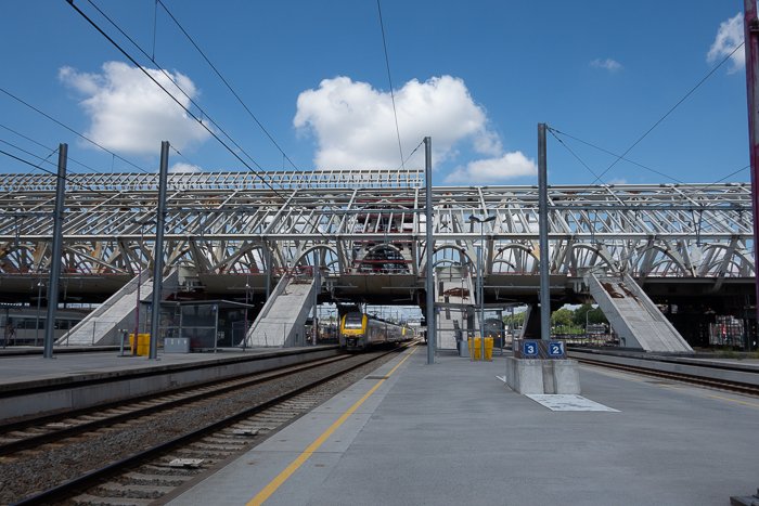 Фотография поезда, подъезжающего к железнодорожной станции в день с голубым небом и облаками