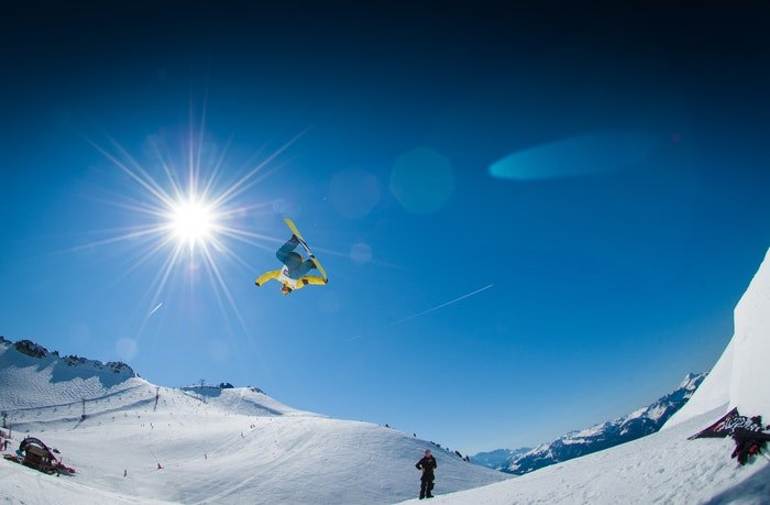 Сноубордист в воздухе над снежными горами
