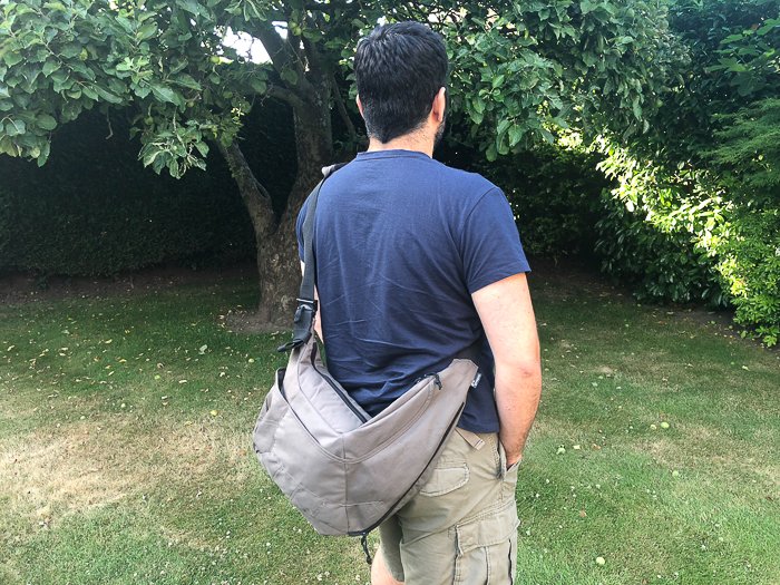 Фотография мужчины, несущего слинговую сумку для камеры
