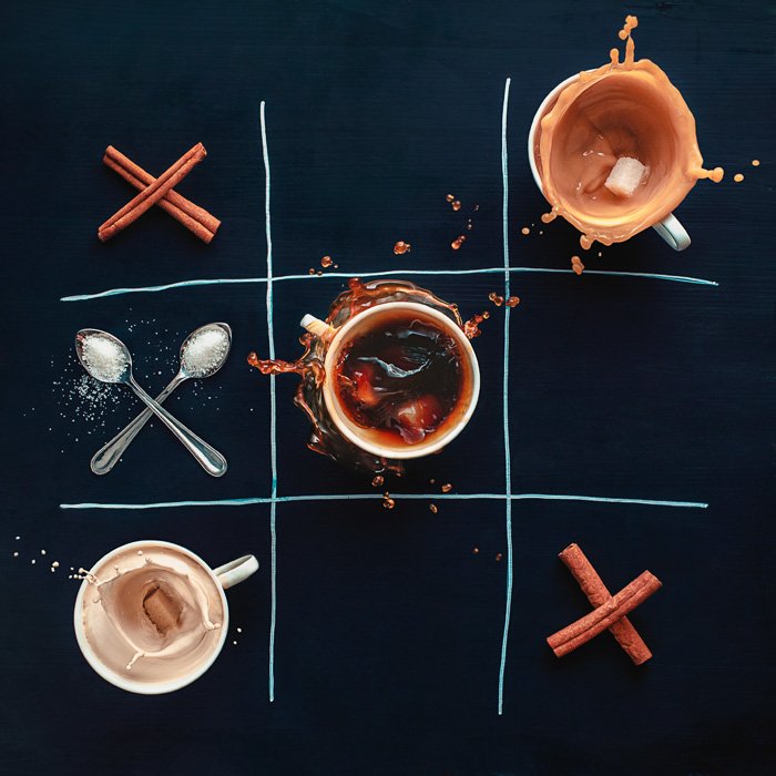 Креативный натюрморт с чашками кофе, палочками корицы и ложками, расположенными в виде сетки