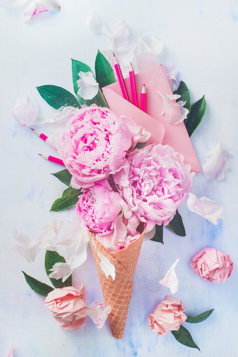 Яркий и воздушный плоский натюрморт с рожком мороженого, наполненным розами, на светлом фоне