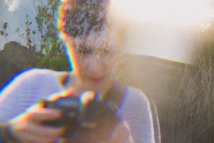 Женщина в полосатом топе держит фотоаппарат, наложенный на фотоэффект 