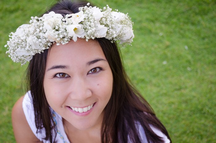 close up of woman wearing a flower crown looking up and smiling