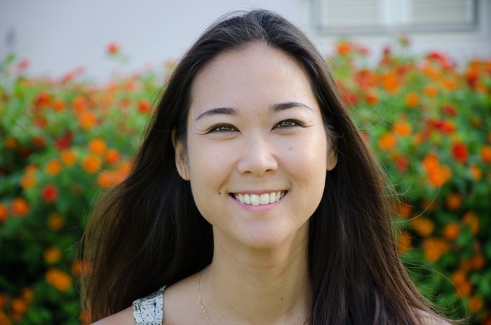 Headshot of smiling asian woman in the field of red flowers