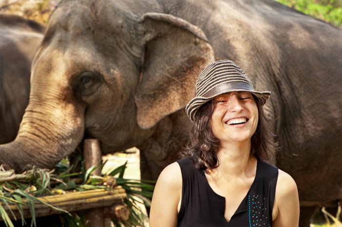 Европейская туристка наслаждается общением со слонами в Национальный день слонов в Таиланде, где их угощают огромным праздником.