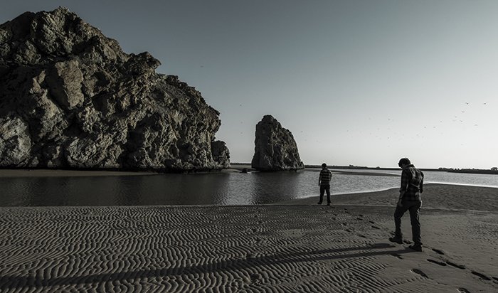 Черно-белый снимок скалистого пляжа с мягким туманным эффектом воды вокруг скал и утесов