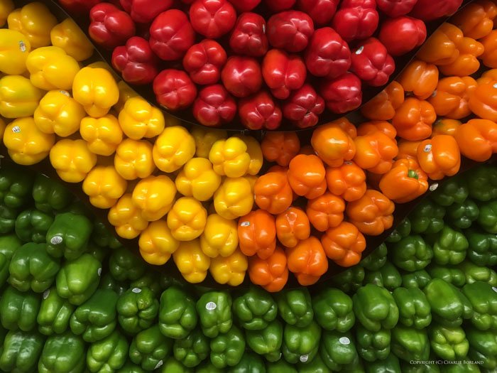 Много зеленых, желтых, красных и оранжевых перцев, расположенных по цветам