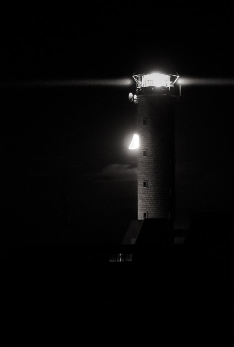 Черно-белая фотография Луны за маяком в Кап-Грис-Нез на фоне черного ночного неба