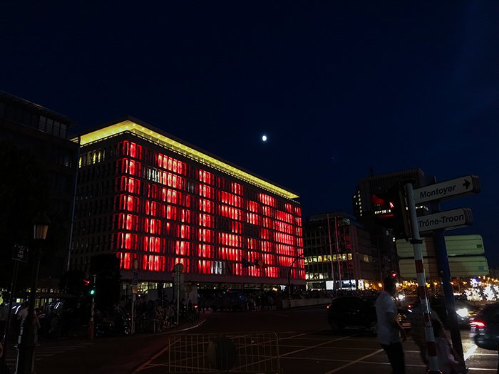 Фотография прямоугольного здания с большим количеством окон ночью, с меняющимися огнями на лицевой стороне