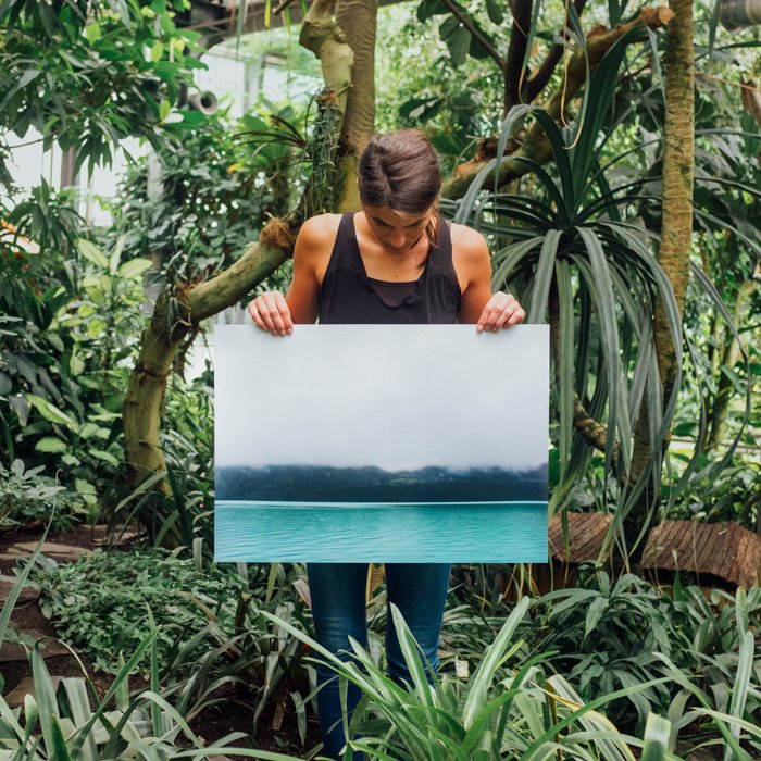 Женщина, стоящая в тропическом лесу, держит в руках фотоотпечаток большого размера