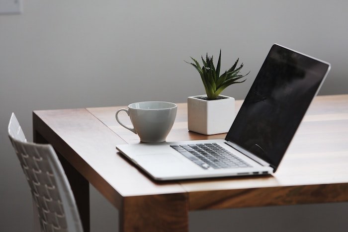 Ноутбук, чашка кофе и растение, установленные на деревянном столе для подготовки бизнес-плана по фотографии