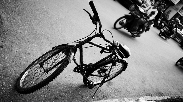 угловая черно-белая фотография велосипеда, припаркованного на улице
