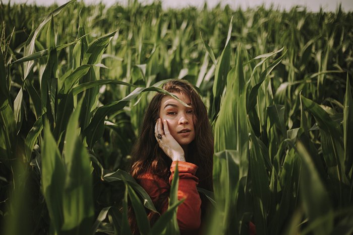 Портрет девушки, позирующей в длинной траве при рассеянном свете облачного дня